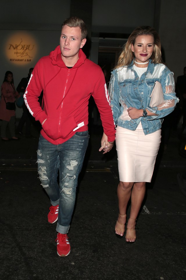 a man in a red hoodie holds hands with a woman in a denim jacket