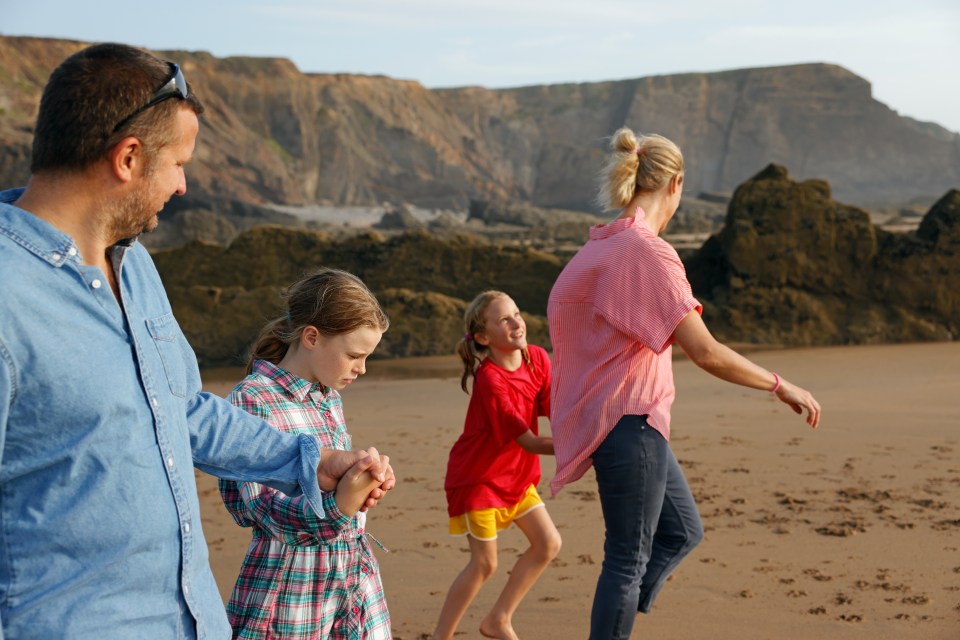 a family walking on the beach holding hands