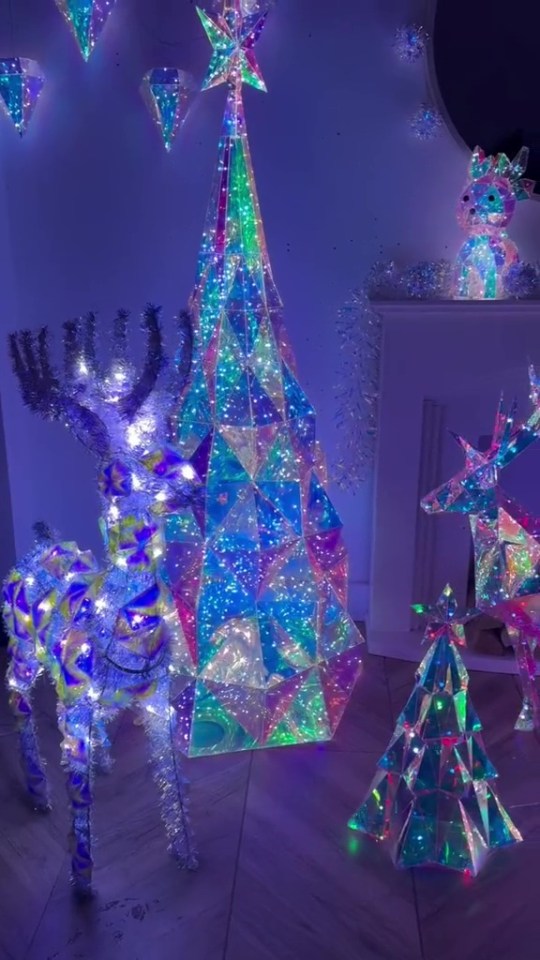 a deer and a christmas tree are lit up in a room