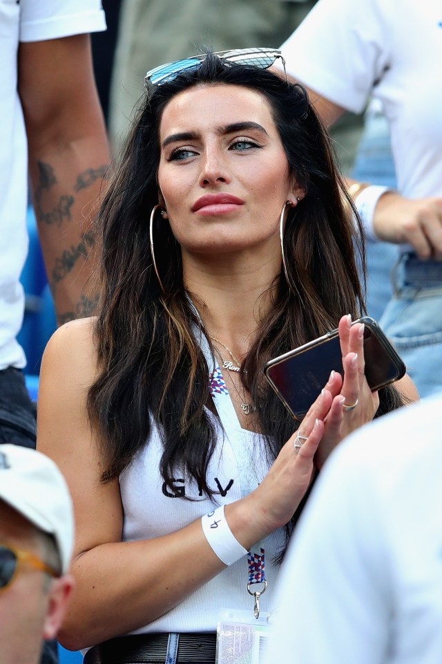 a woman wearing a white tank top with the letter g on it