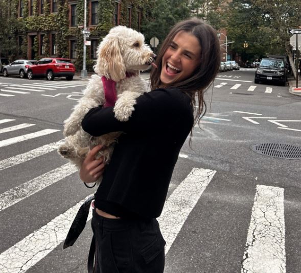 a woman is holding a small white dog in her arms