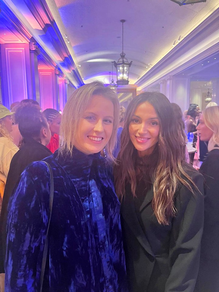 two women posing for a picture in a crowded room