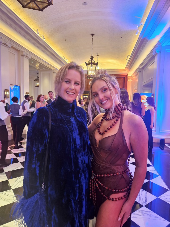 two women are posing for a picture in a hallway