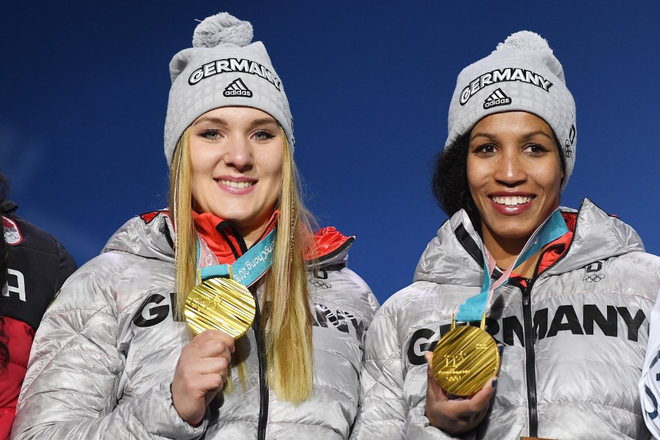 two women wearing germany hats hold up their gold medals