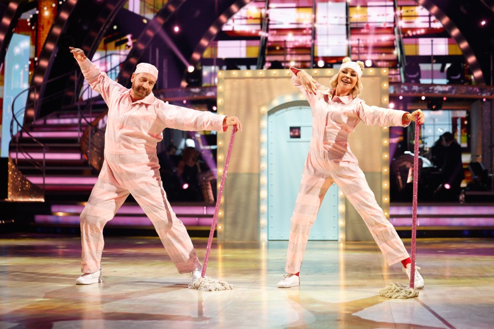 a man and a woman are dancing on a stage with mop handles