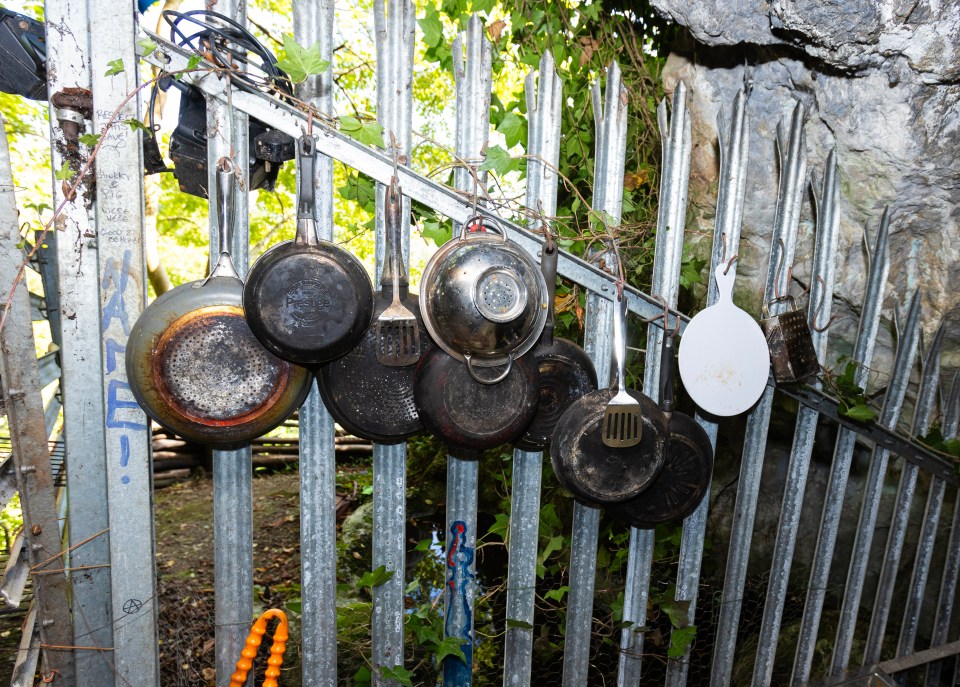 a bunch of pots and pans are hanging on a metal fence