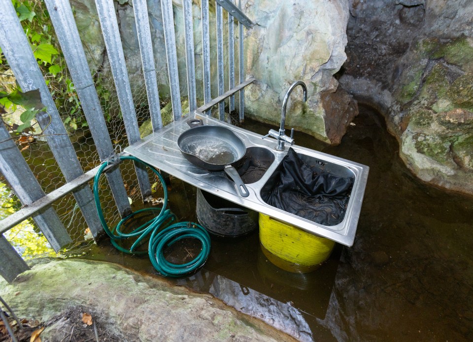 a sink with a frying pan and a green hose attached to it