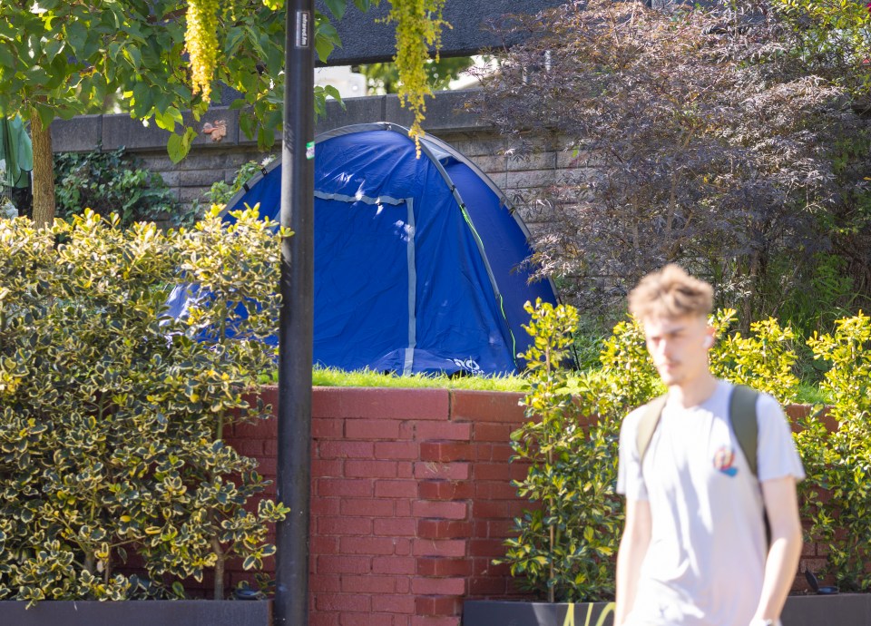 a man walking past a blue tent that says no on it