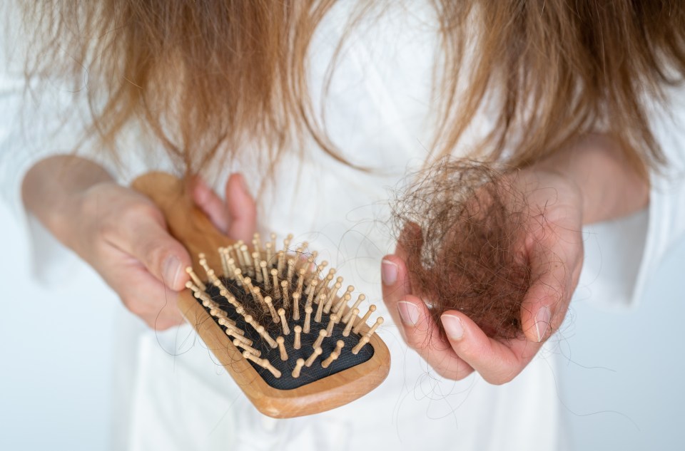 a woman is holding a brush and a bunch of hair