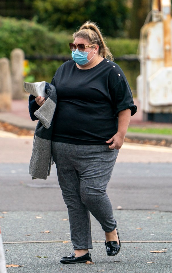 a woman wearing a mask and sunglasses walks down the street