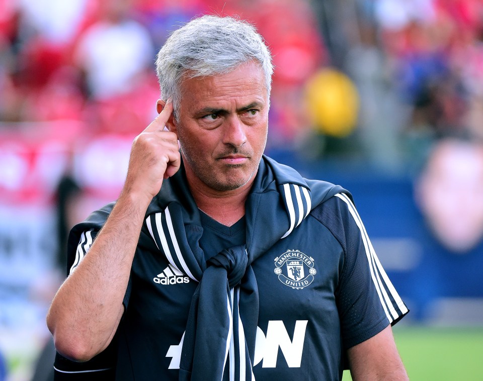 a man wearing a manchester united jersey holds his hand to his ear