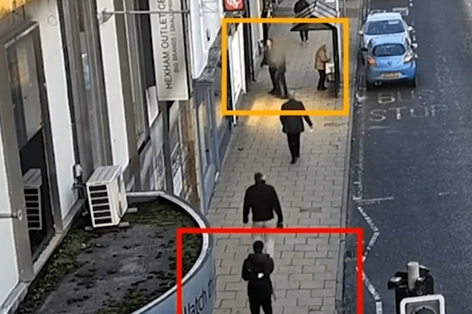 people walking down a sidewalk next to a bus stop