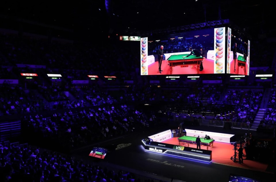 a snooker match is being shown on a large screen