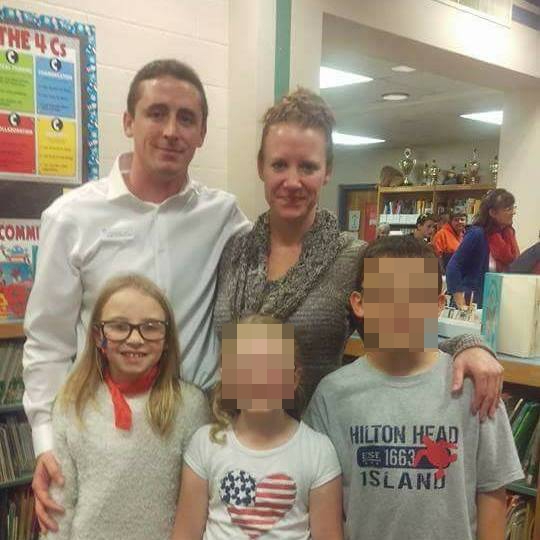 a man and woman are posing for a picture with two children in a library .