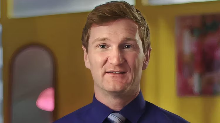 a man in a blue shirt and tie looks at the camera