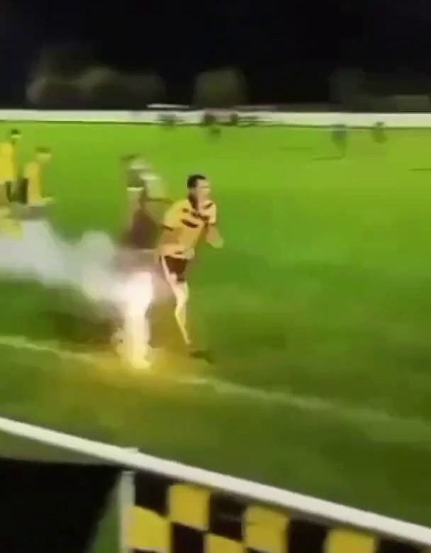 a man is running on a soccer field with a fireball in the background .