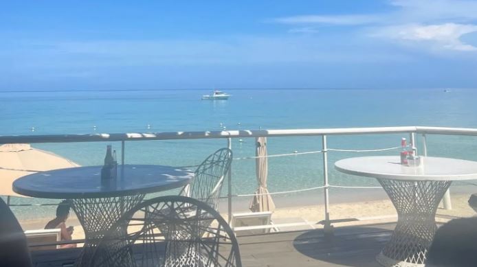 two tables and chairs on a balcony overlooking the ocean