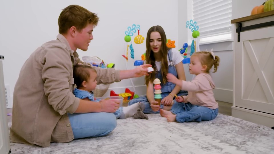 a family sits on the floor playing with toys