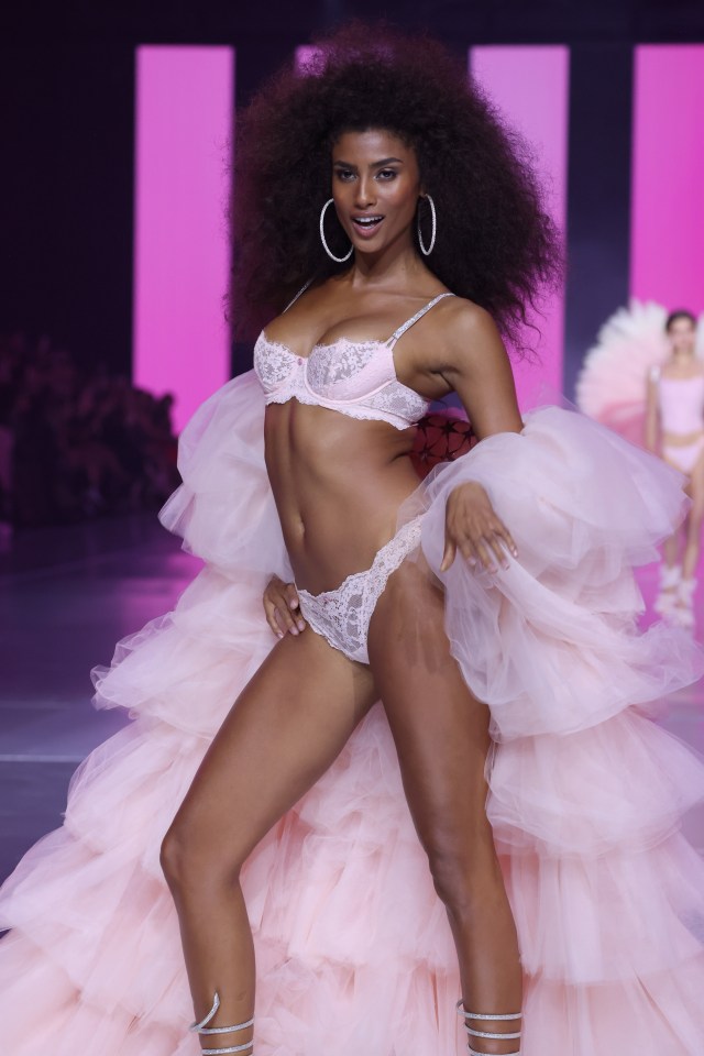 a woman in lingerie is walking down a runway