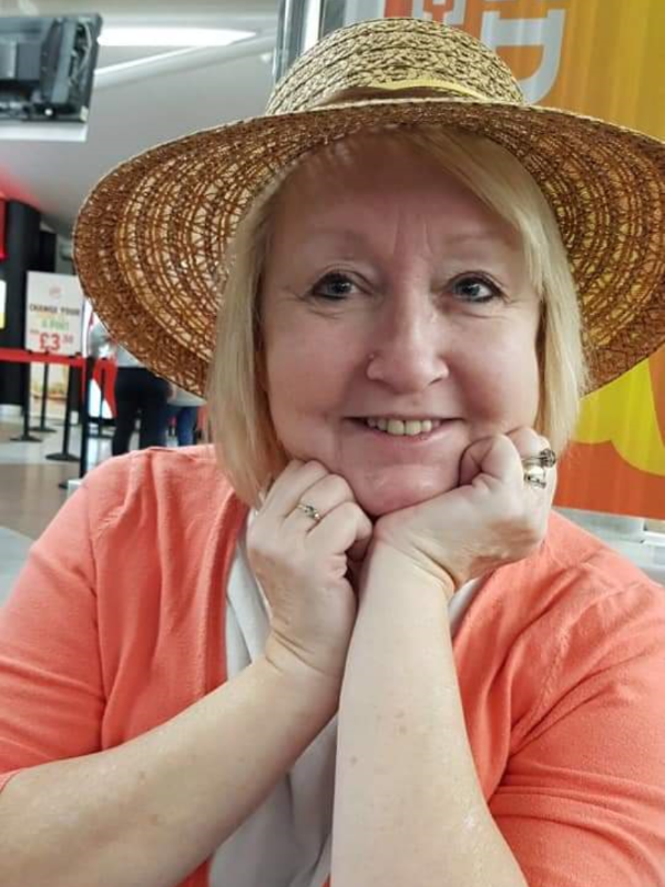 a woman wearing a straw hat is smiling with her hands on her face