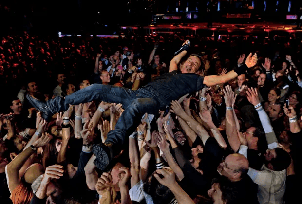 a man is being lifted in the air by a crowd at a concert