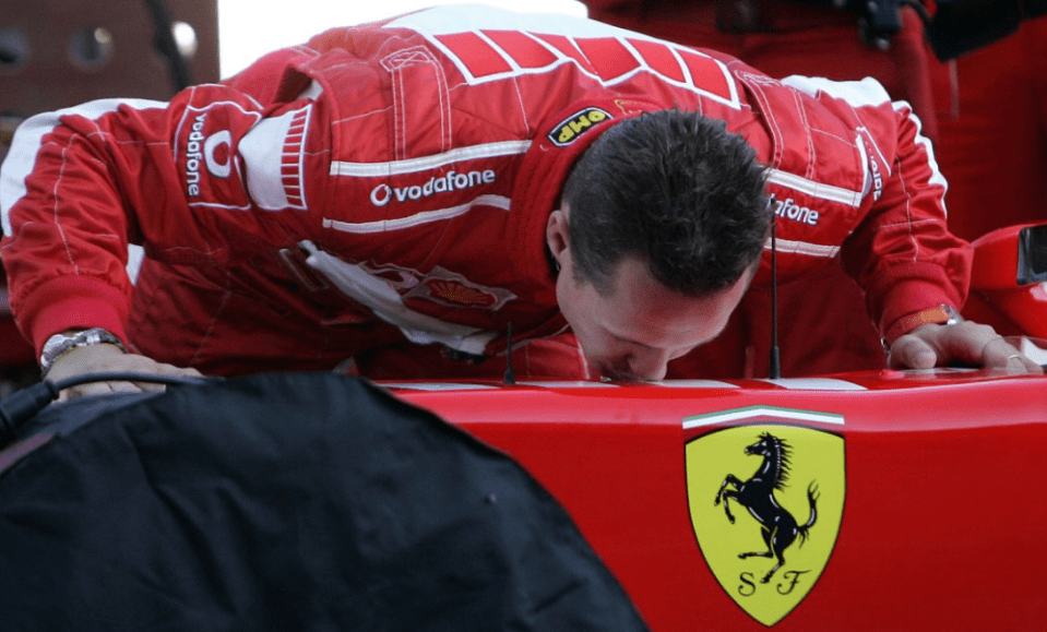 a man in a vodafone shirt kisses a red ferrari