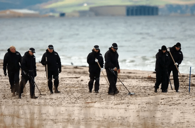 a group of police officers are searching the sand on a beach