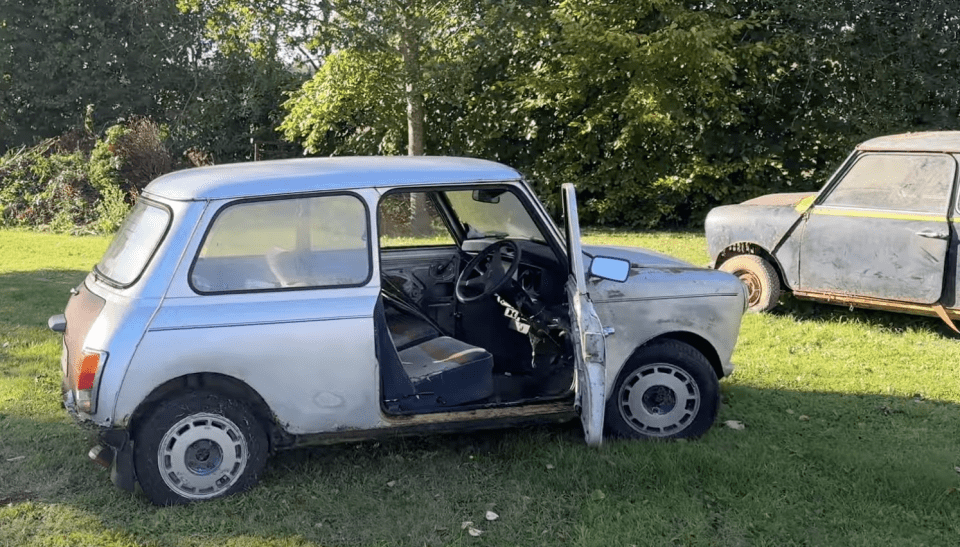 a silver car with the door open is parked in the grass