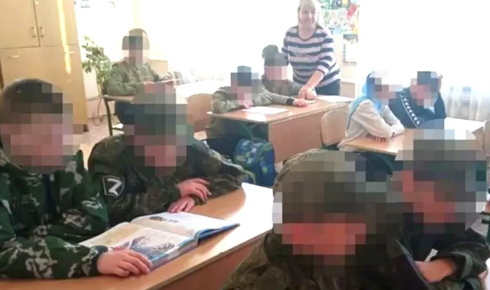 a group of children in military uniforms are sitting at desks in a classroom .