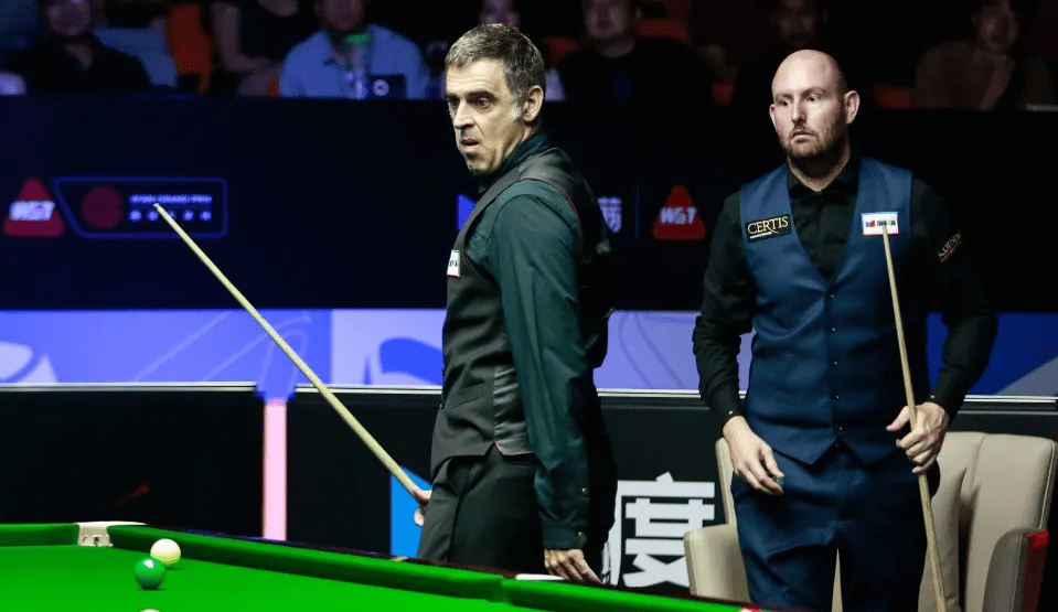 two men playing snooker with one wearing a vest that says certus