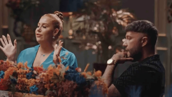 a man and a woman are sitting at a table with flowers .