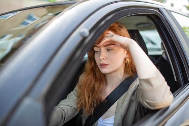 a woman with red hair is sitting in a car with her hand on her forehead