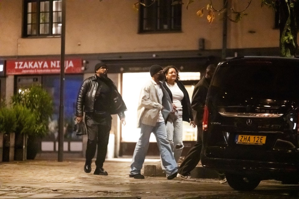 a group of people walking in front of a store called izakaya ni ja