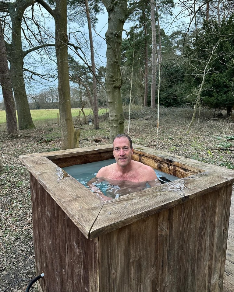 a man is sitting in a wooden tub with trees in the background