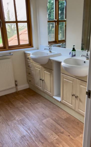 a bathroom with two sinks , a mirror and a window .