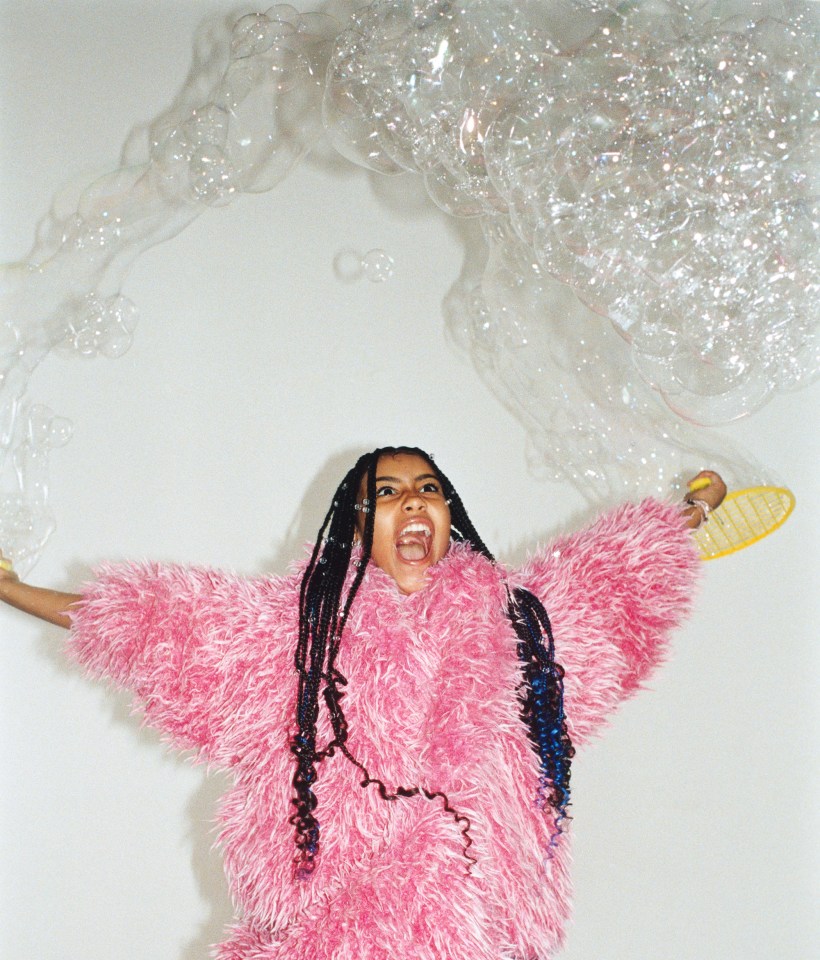 a woman in a pink fluffy sweater is surrounded by bubbles