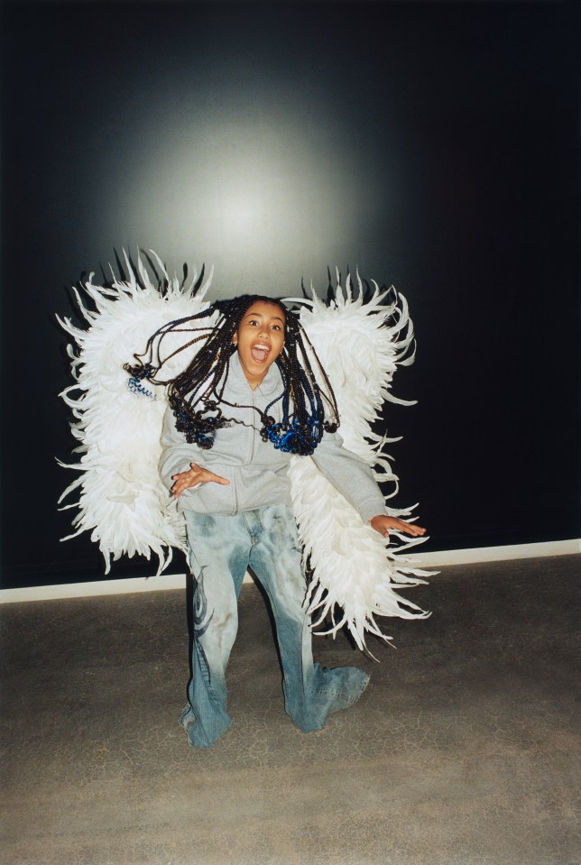 a young girl wearing a grey jacket and white feathered wings