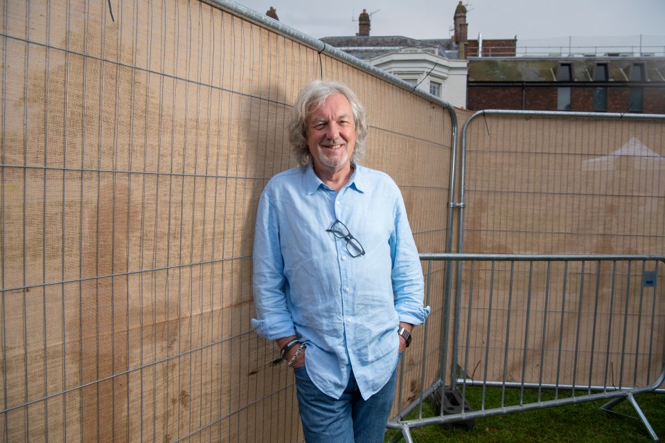 a man in a blue shirt is leaning against a fence