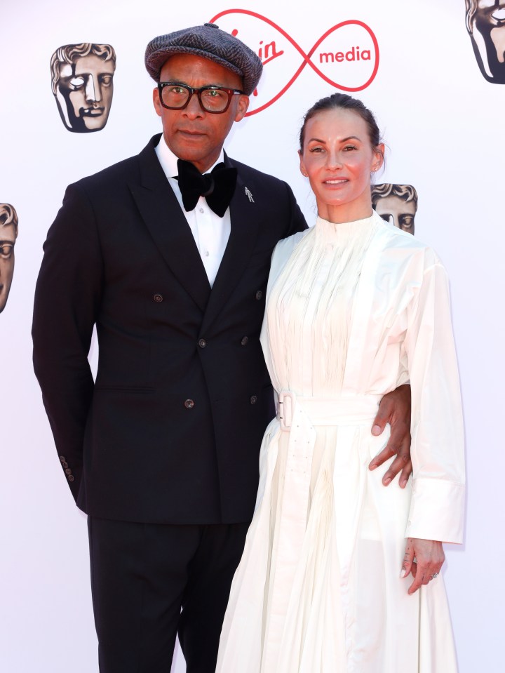 a man and a woman pose on a red carpet in front of a virgin media logo