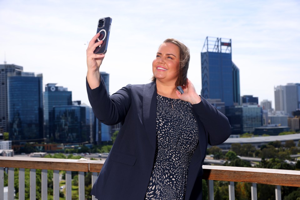 a woman taking a selfie with a city skyline in the background