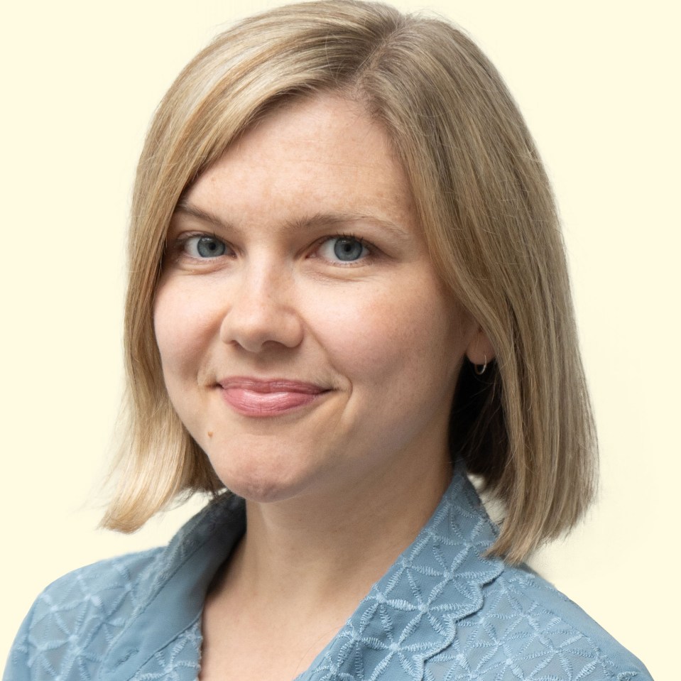 a woman in a blue shirt smiles for the camera