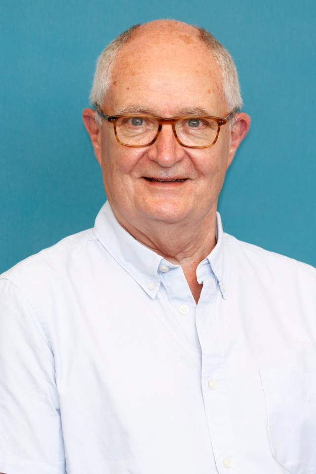 a man wearing glasses and a white shirt smiles for the camera