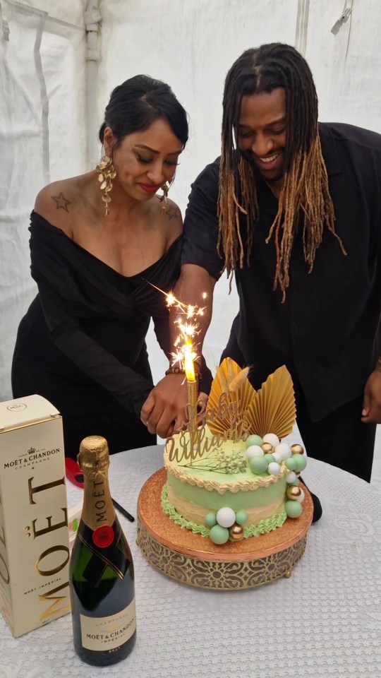 a man and woman cutting a cake next to a bottle of moet