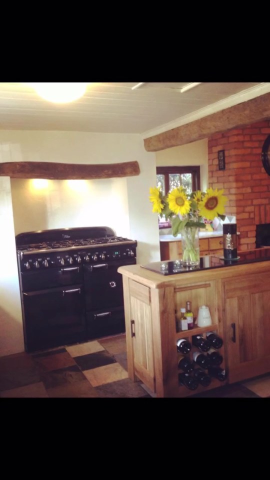 a kitchen with a black stove and a vase of sunflowers