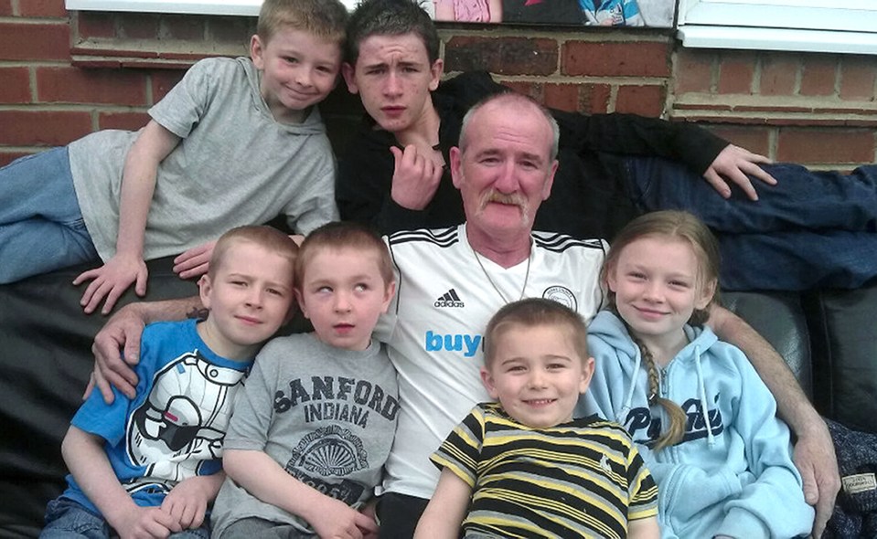 a man wearing a sanford indiana shirt is surrounded by children