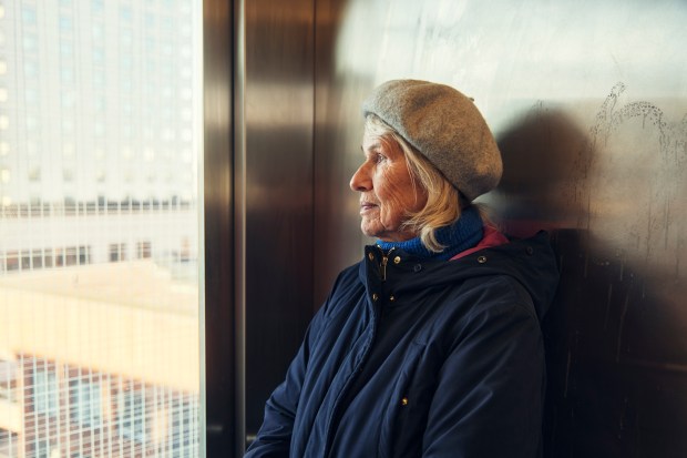 a woman wearing a beret and a jacket looks out a window