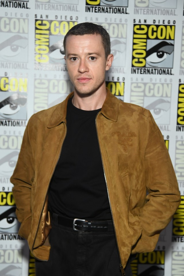 a man stands in front of a wall that says comic con