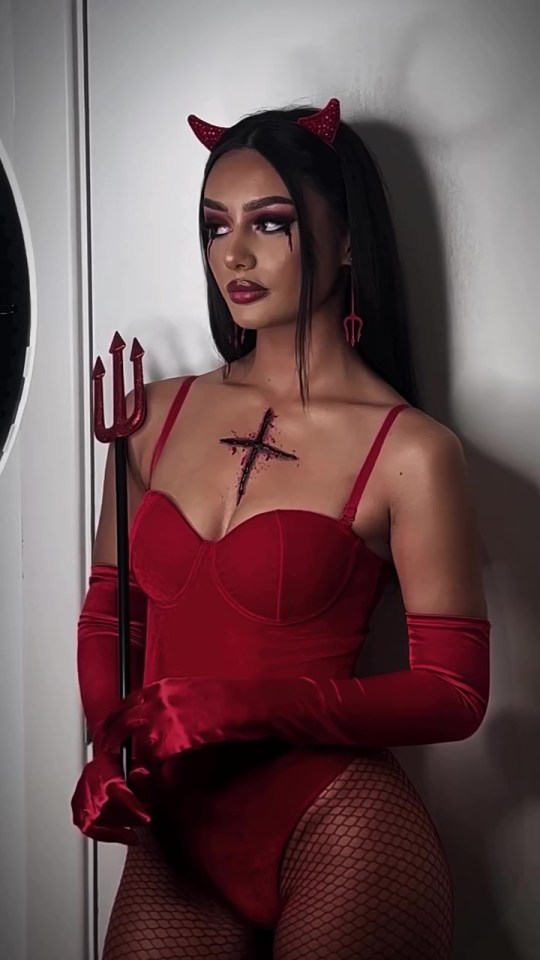 a woman in a devil costume is holding a trident