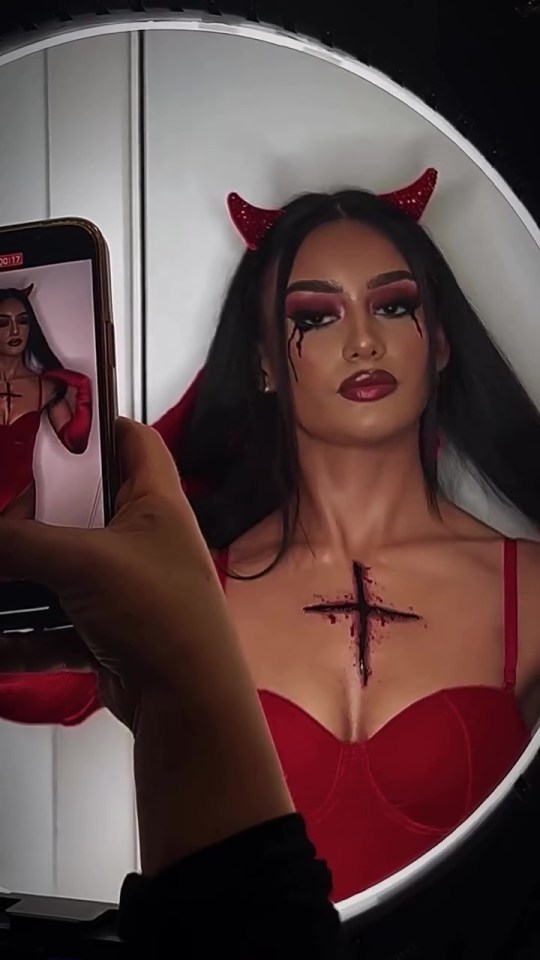 a woman in a devil costume is taking a picture of herself