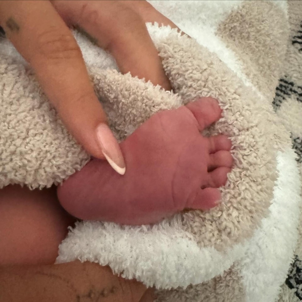 a woman holds a baby 's foot on a blanket